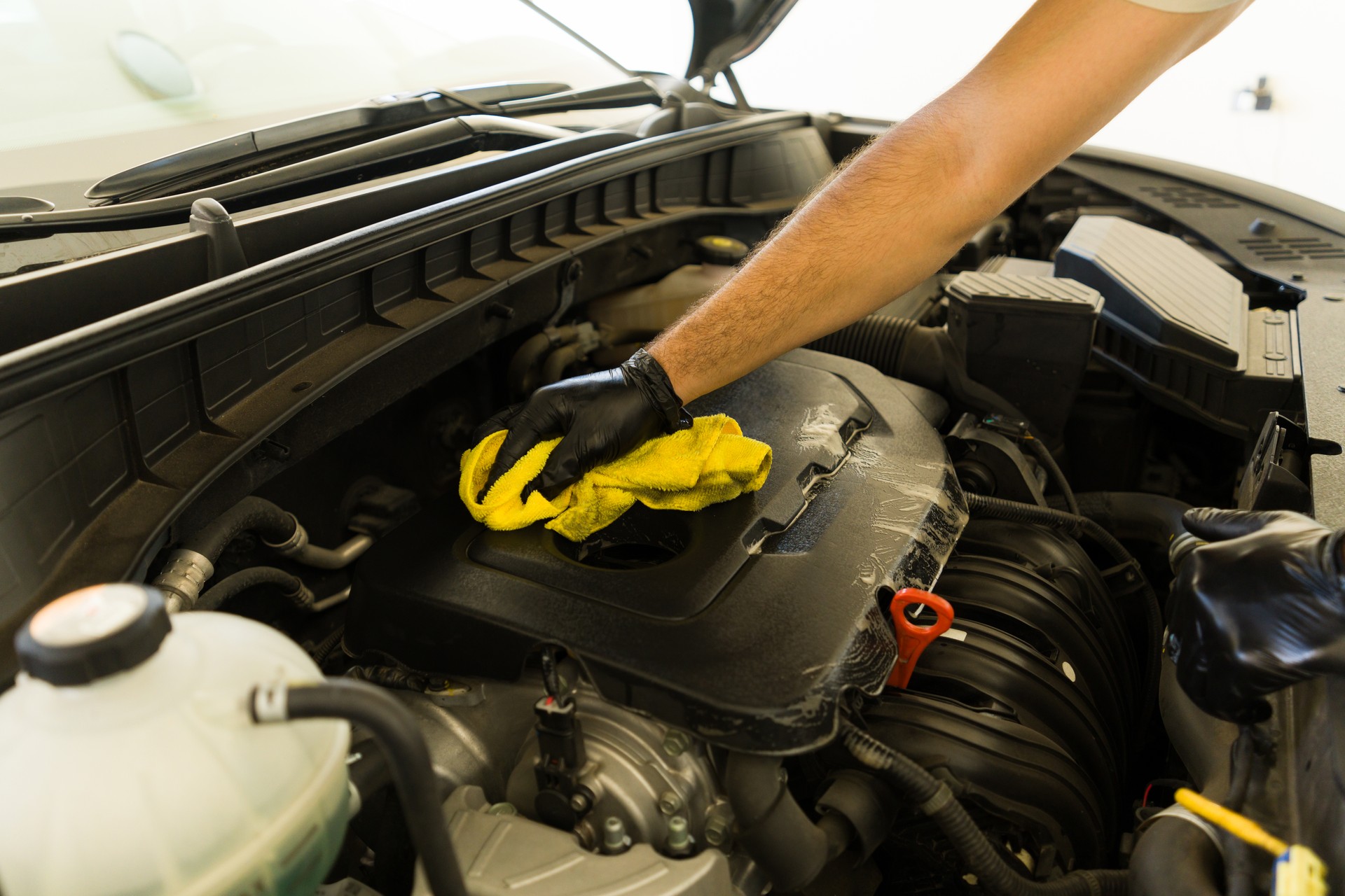 Car wash service worker cleaning vehicle engine